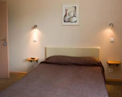 a bedroom with a bed and two lights on the wall at Les Orangers in Aléria