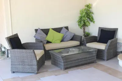 a patio with wicker chairs and a couch and a table at Les Orangers in Aléria