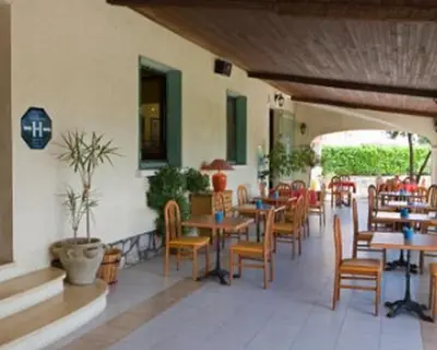 a restaurant with tables and chairs in a room at Les Orangers in Aléria