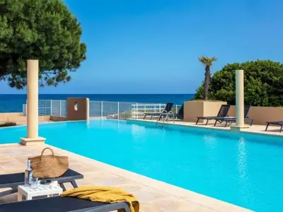 a swimming pool with chairs and the ocean in the background at Apartment MB6 Loggia by Interhome in Moriani Plage