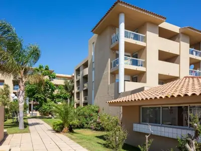 a large apartment building with a pathway and palm trees at Apartment MB6 Loggia by Interhome in Moriani Plage