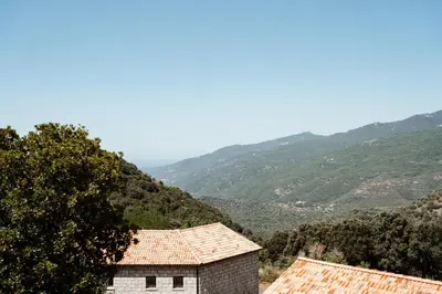 a view of two buildings with mountains in the background at U Parasu in Santa-Maria-Figaniella