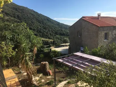 a house with a solar panel next to a mountain at U Parasu in Santa-Maria-Figaniella