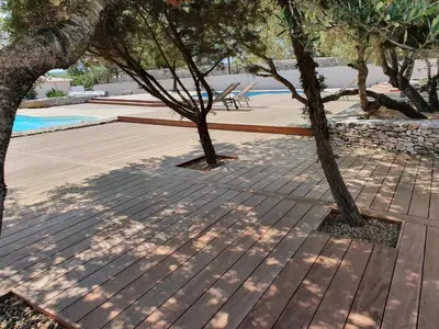 a wooden deck with trees and a swimming pool at CHALET CANAVA in Bonifacio