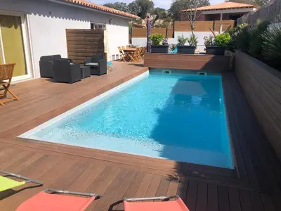 a swimming pool with a wooden deck and a swimming poolvisor at Villa Orethaga Piscine 10 pers porto Vecchio in Porto-Vecchio