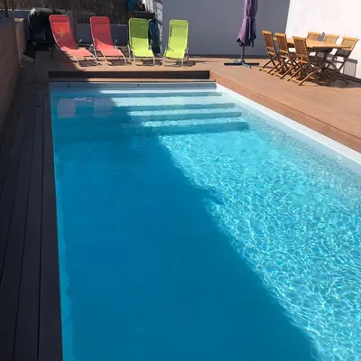 a swimming pool with blue water and colorful chairs at Villa Orethaga Piscine 10 pers porto Vecchio in Porto-Vecchio