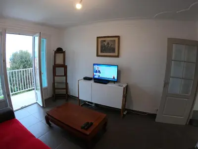 a living room with a red couch and a television at LA TERRASSE DE SAINT-JEAN in Ajaccio
