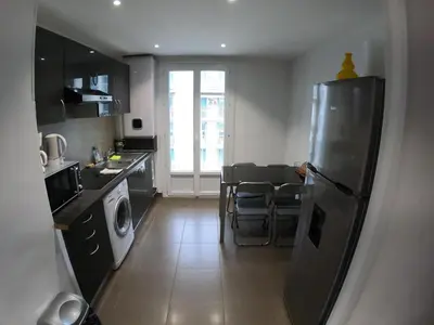 a kitchen with a refrigerator and a table with chairs at LA TERRASSE DE SAINT-JEAN in Ajaccio