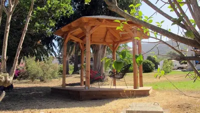 a wooden gazebo with a chair in a park at Residence Maïna in Cargèse