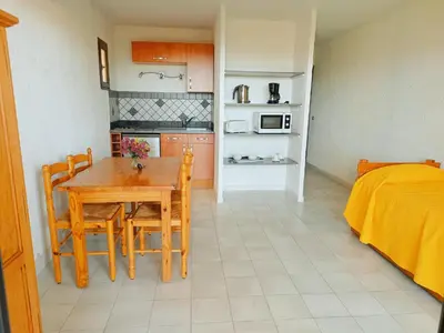 a kitchen with a table and chairs and a bed at Residence Maïna in Cargèse