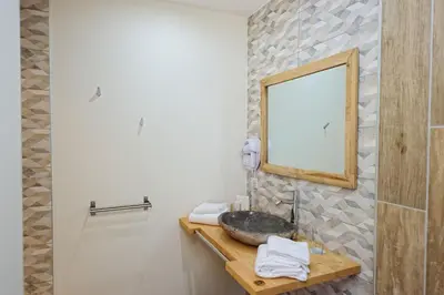 a bathroom with a stone sink and a mirror at Hotel Le Tourisme in Zonza
