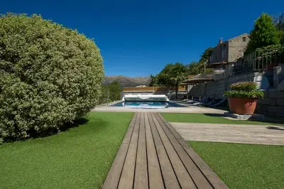 a wooden bench in a yard with a pool at Hotel Le Tourisme in Zonza