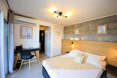 a bedroom with a bed and a desk and a chair at Hotel Le Tourisme in Zonza