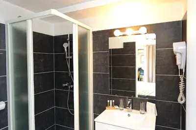 a bathroom with a shower and a sink and a mirror at Hotel Le Tourisme in Zonza