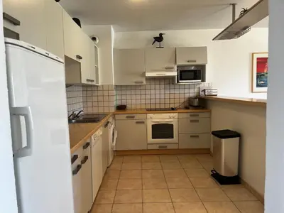 a small kitchen with white cabinets and appliances at PALMERAIE 220 in Sari Solenzara