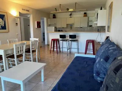 a living room with a table and chairs and a kitchen at PALMERAIE 220 in Sari Solenzara