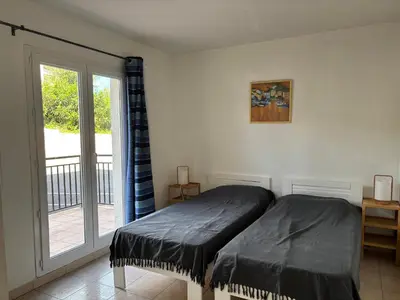 a bedroom with a bed and a sliding glass door at PALMERAIE 220 in Sari Solenzara