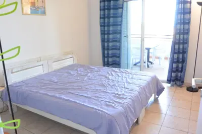 a bedroom with a bed with a blue comforter at PALMERAIE 325 in Sari Solenzara