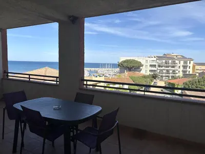 a table and chairs in a balcony with a view of the ocean at PALMERAIE 325 in Sari Solenzara