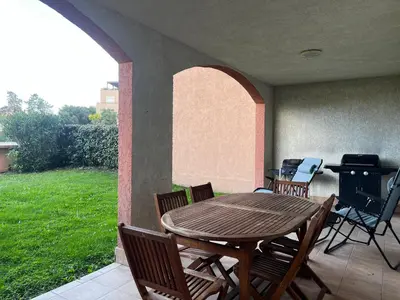 a patio with a table and chairs and a grill at PALMERAIE 412- piscine en résidence-clim-wifi in Sari Solenzara