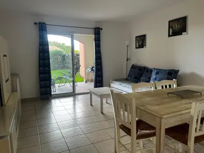 a living room with a table and chairs and a couch at PALMERAIE 412- piscine en résidence-clim-wifi in Sari Solenzara