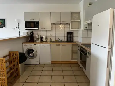 a kitchen with a white refrigerator and a dishwasher at PALMERAIE 412- piscine en résidence-clim-wifi in Sari Solenzara