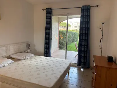 a bedroom with a bed and a sliding glass door at PALMERAIE 412- piscine en résidence-clim-wifi in Sari Solenzara