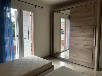 a bedroom with a sliding glass door and a bed at PALMERAIE 412- piscine en résidence-clim-wifi in Sari Solenzara