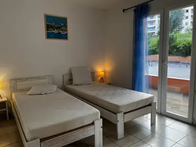 a bedroom with two twin beds and a window at PALMERAIE 412- piscine en résidence-clim-wifi in Sari Solenzara