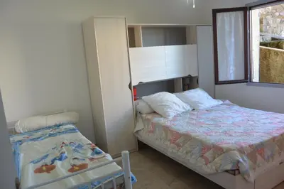 a small bedroom with a bed and a window at FIUMICELLI in Sari Solenzara