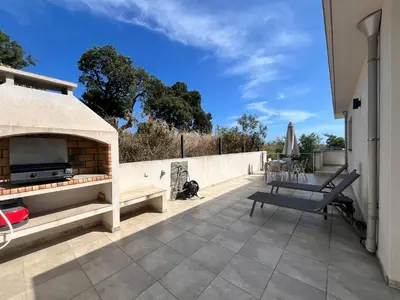 a patio with a fireplace and a table and a chair at SOLEIL ROUGE in Sari Solenzara