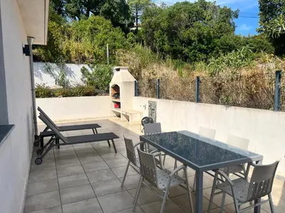 a patio with a table and chairs and a pizza oven at SOLEIL ROUGE in Sari Solenzara