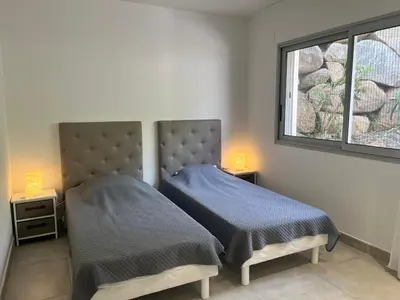 a bedroom with two beds and a window at SOLEIL ROUGE in Sari Solenzara