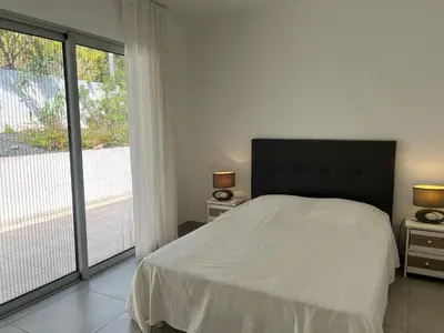 a bedroom with a bed and a large window at SOLEIL ROUGE in Sari Solenzara