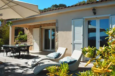 a patio with a table and chairs and an umbrella at Résidence Ogliastrello in Olmeto