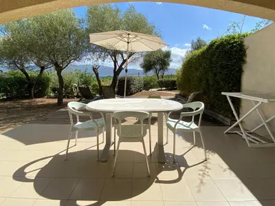 a white table with chairs and an umbrella on a patio at Résidence Ogliastrello in Olmeto