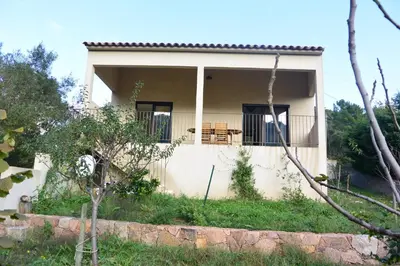 a small white house with a balcony with a table at FILETTA in Sari Solenzara