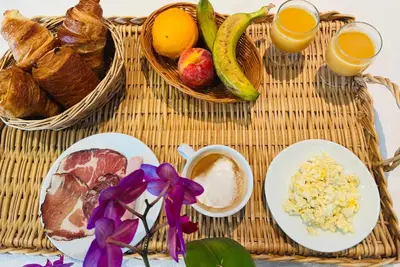 a rattan table with a breakfast of bread and fruit at Sun Beach in Ajaccio