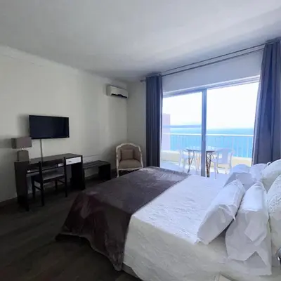 a hotel room with a bed and a desk and a window at Sun Beach in Ajaccio
