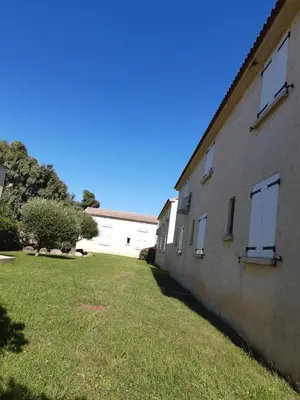 a building with white windows and a grass yard at Résidence Pascal Paoli Fior di Mare in Moriani Plage