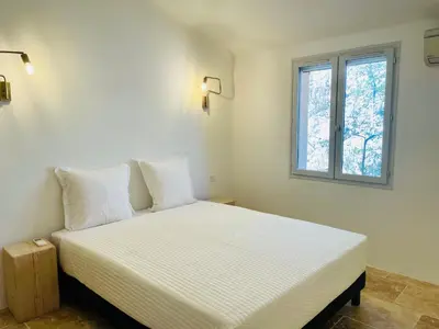 a bedroom with a white bed with a window at Domaine Pietra di Sole in Porto-Vecchio