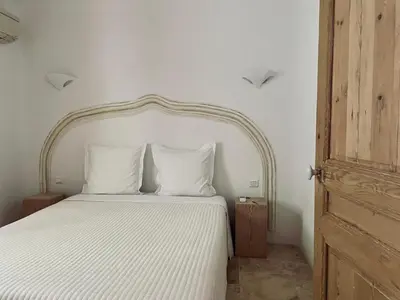 a bedroom with a white bed with an ornate headboard at Domaine Pietra di Sole in Porto-Vecchio