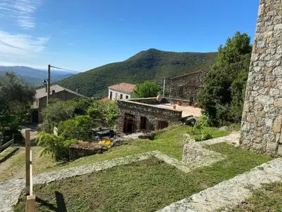an old stone building with a mountain in the background at Résidence Casa Di Roc in Urtaca