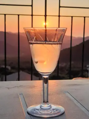 a wine glass sitting on a table with the sunset in the background at Résidence Casa Di Roc in Urtaca
