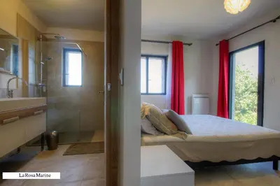a bedroom with a bed and a bathroom with red curtains at Résidence Casa Di Roc in Urtaca