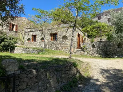 an old stone house with a tree in front of it at Résidence Casa Di Roc in Urtaca
