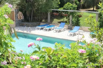 a swimming pool with two chairs and two tables and chairs at Domaine Le Clos des Oliviers in Sorbo-Ocagnano