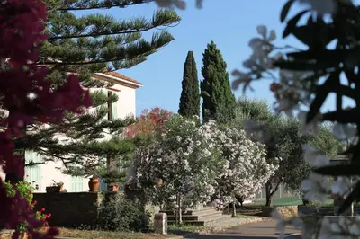 a house with trees and flowers in front of it at Domaine Le Clos des Oliviers in Sorbo-Ocagnano