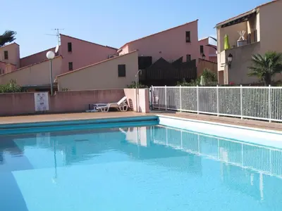 a swimming pool with blue water in front of some buildings at MARE BELLU AGOSTA PLAGE in Albitreccia