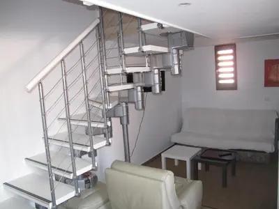 a staircase in a living room with a chair and a couch at MARE BELLU AGOSTA PLAGE in Albitreccia